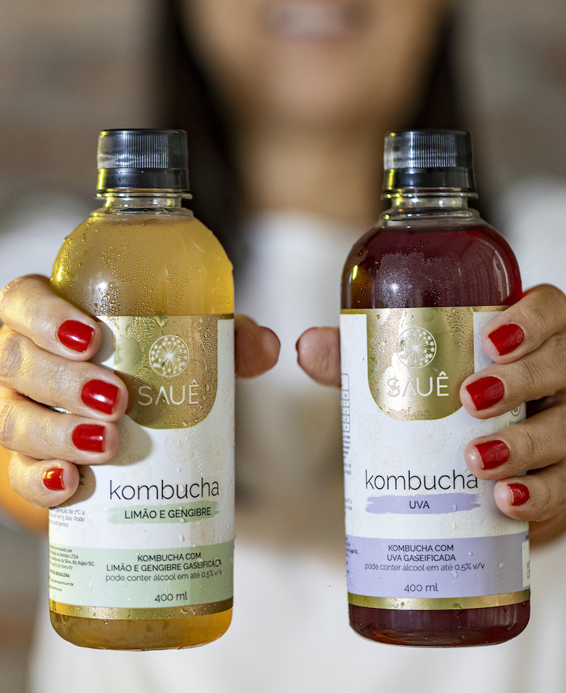 Mulher segurando garrafas de kombucha da Sauê